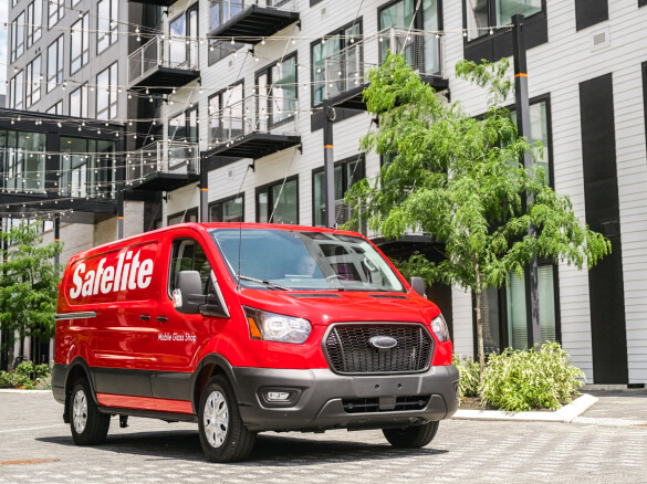 Photo of a Safelite van parked next to a residential building.